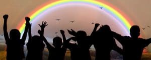 Silhouettes of children in front of a rainbow.