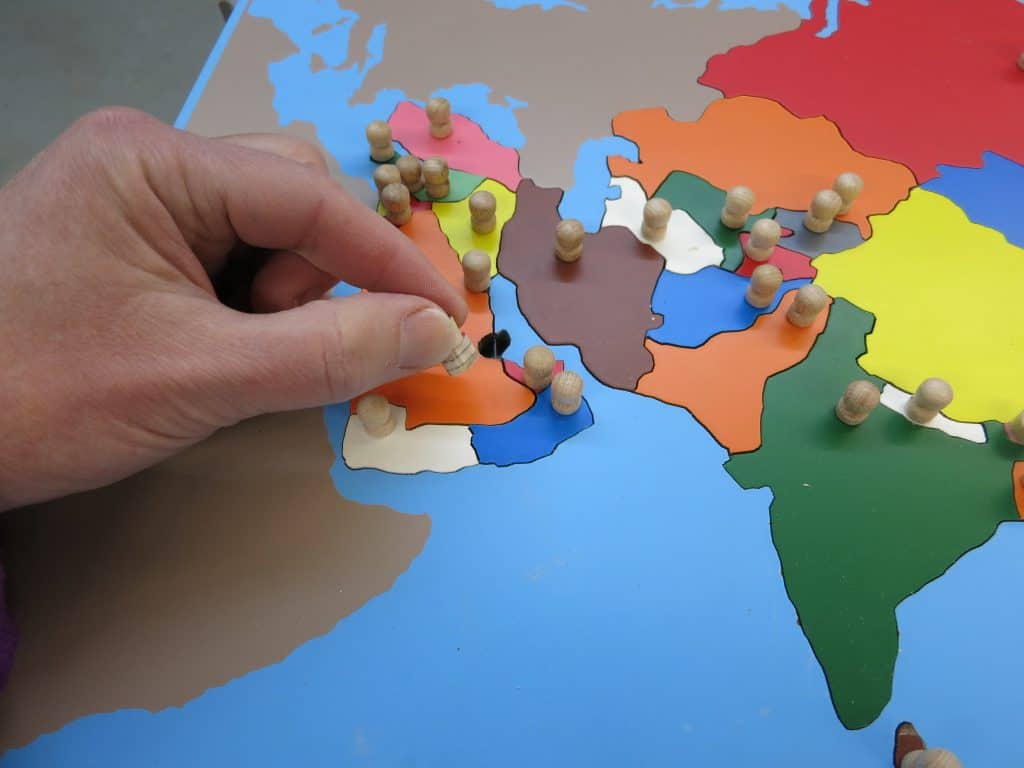 Montessori puzzle map showing the pincer grip of picking up a piece.