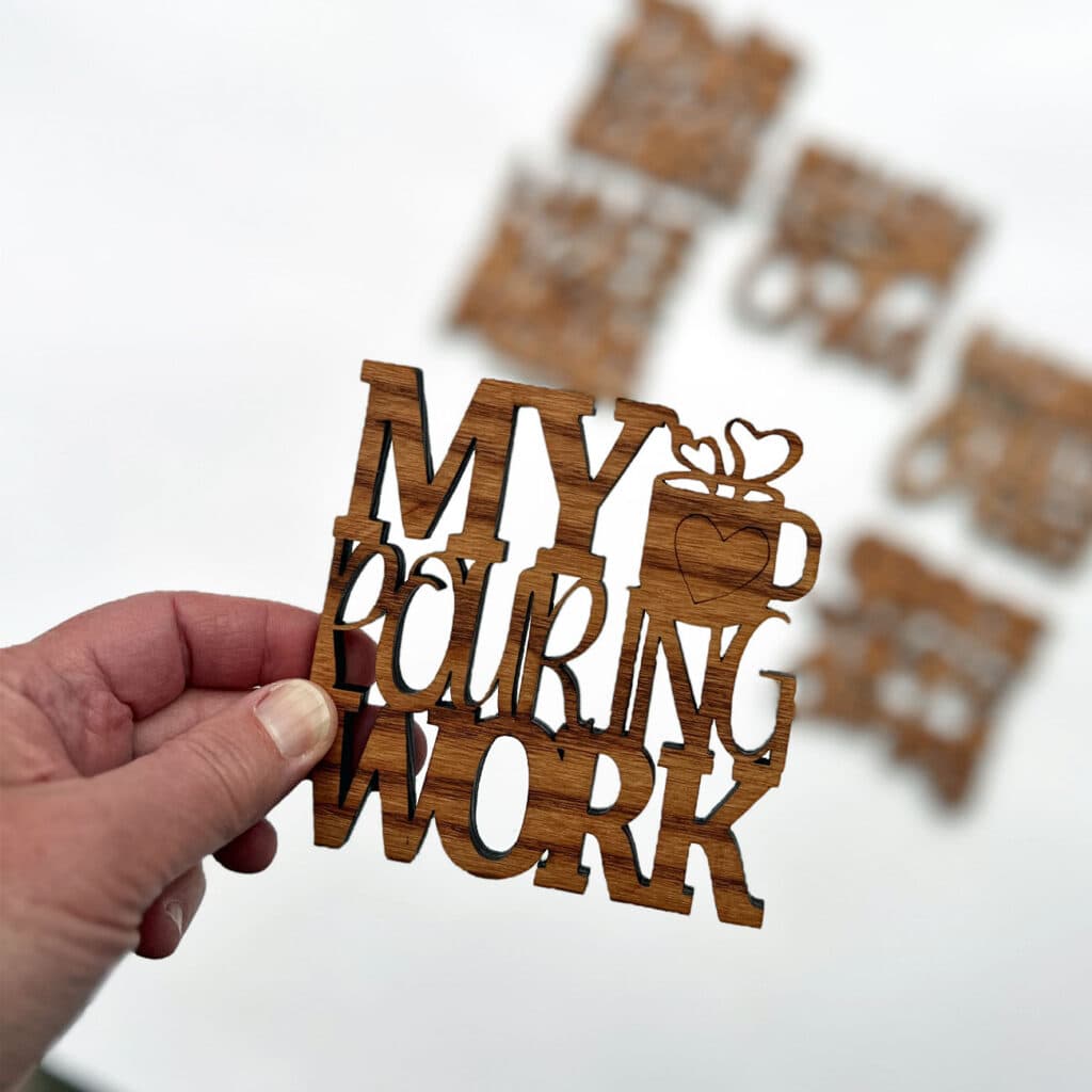 Hand holding coaster with blurred images of other coasters in background.