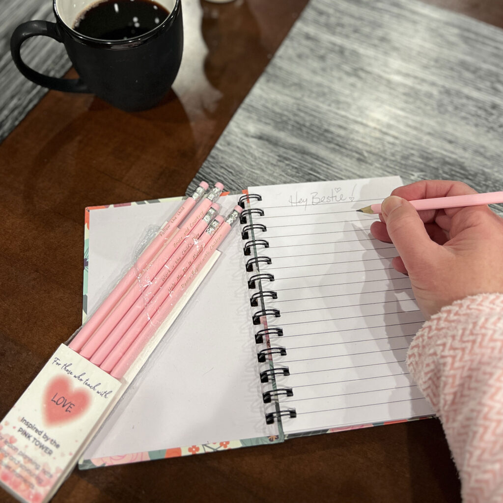 Using the pink pencils to write in a notebook.